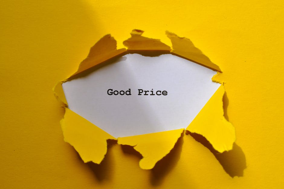A torn yellow paper reveals a white interior note with the words 'Good Price' typed in black text. The torn edges of the paper are irregular, with some flaps curling outward, exposing the note inside. The background is a solid yellow color, enhancing the visibility of the torn paper. The image conveys a sense of revealing value or affordability, consistent with home relocation and packing processes involved in removals services. The scene is well-lit, with shadows cast by the torn paper edges, emphasizing the three-dimensional aspect of the torn cardboard or paper material. This visual could be associated with transparent pricing or cost-effective moving solutions offered by Man with Van Osterley during furniture transport or packing and moving tasks.